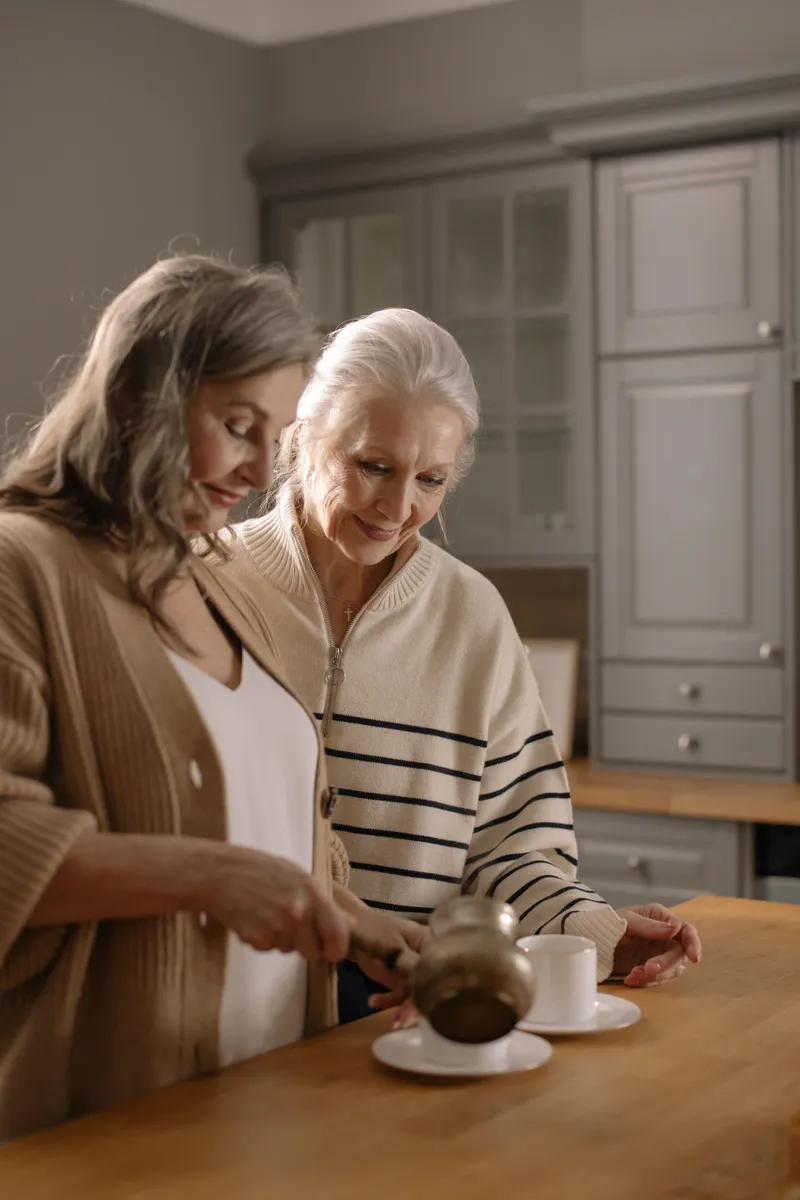 Caregiver pushing a senior client in a wheelchair across a sunlit field