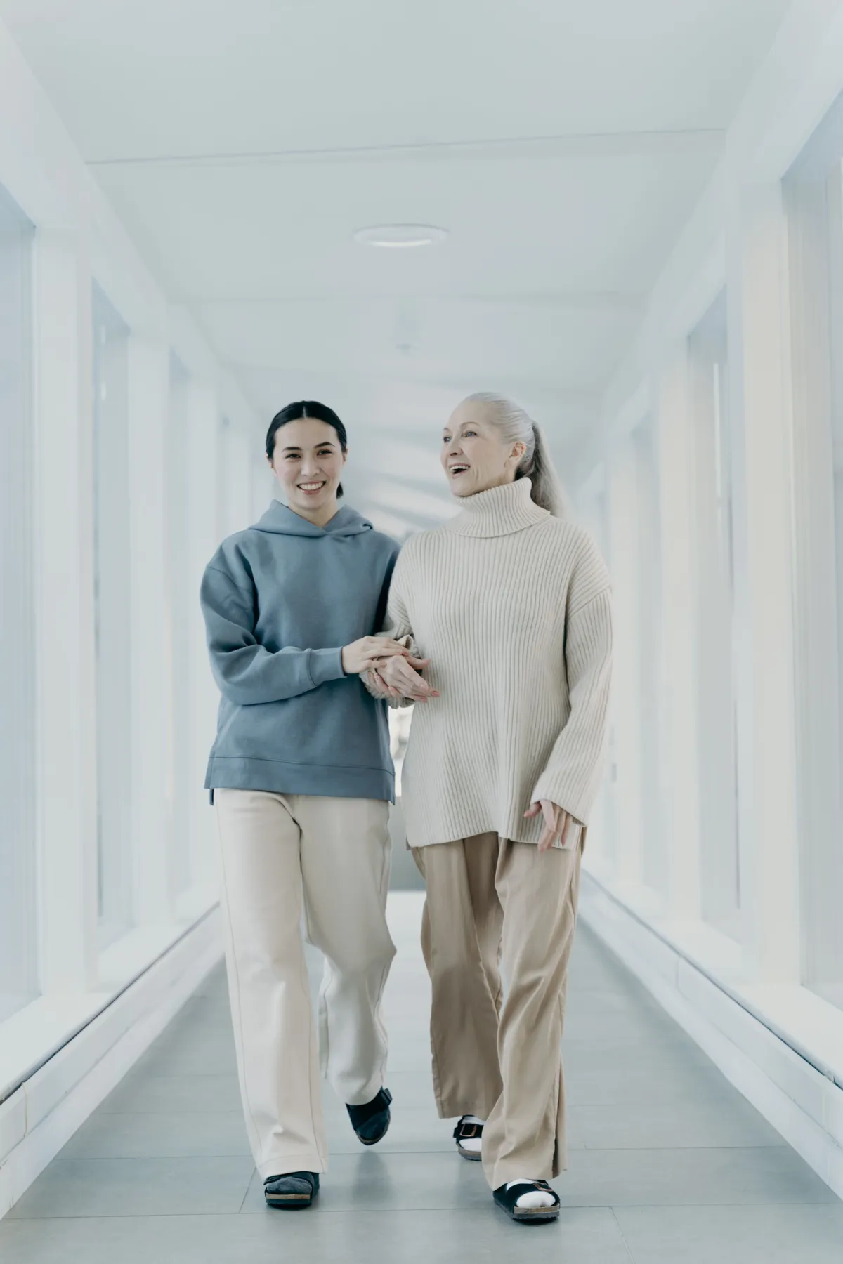 A caregiver walking arm in arm with a smiling senior woman