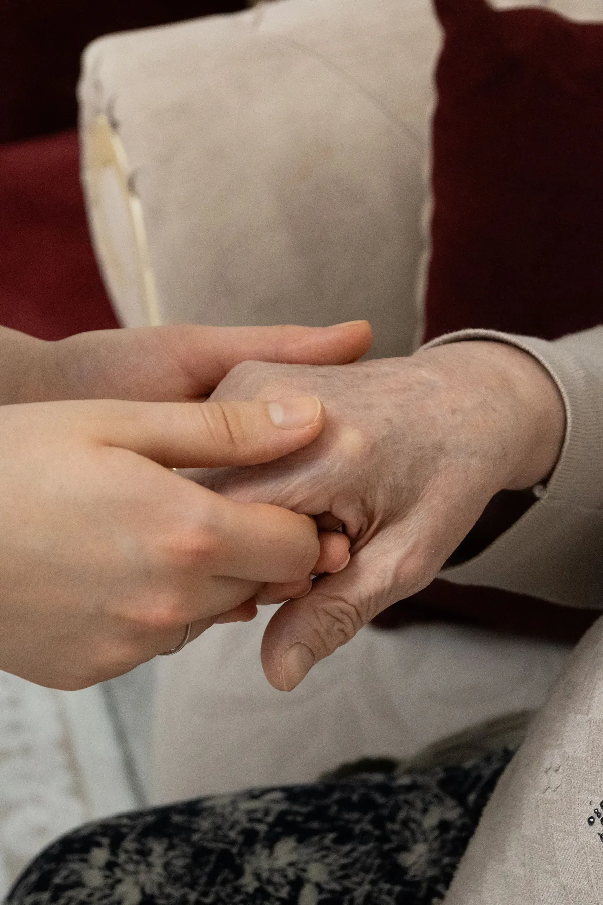 A younger hand resting gently on the hand of an older person
