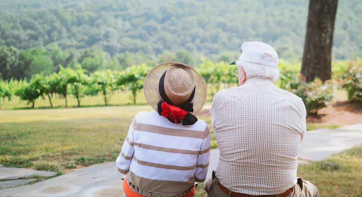 An older couple sitting together looking out over a vineyard