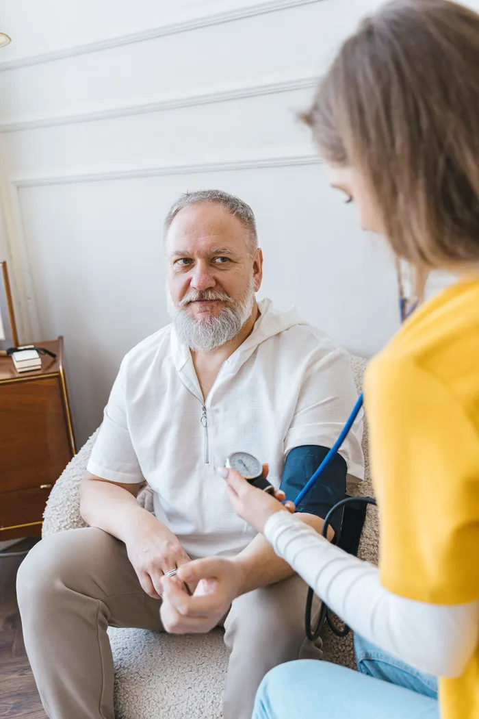 Caregiver taking a senior man's blood pressure at home