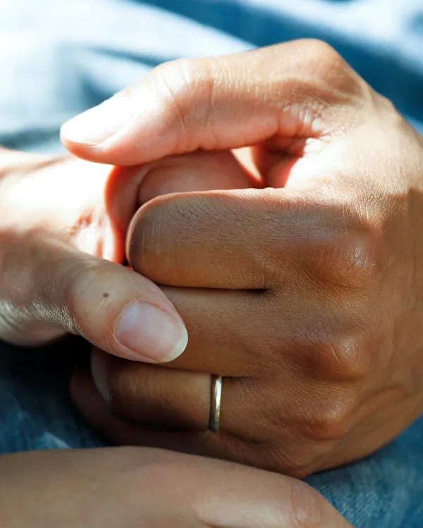 A caregiver's hands gently holding a senior's hand
