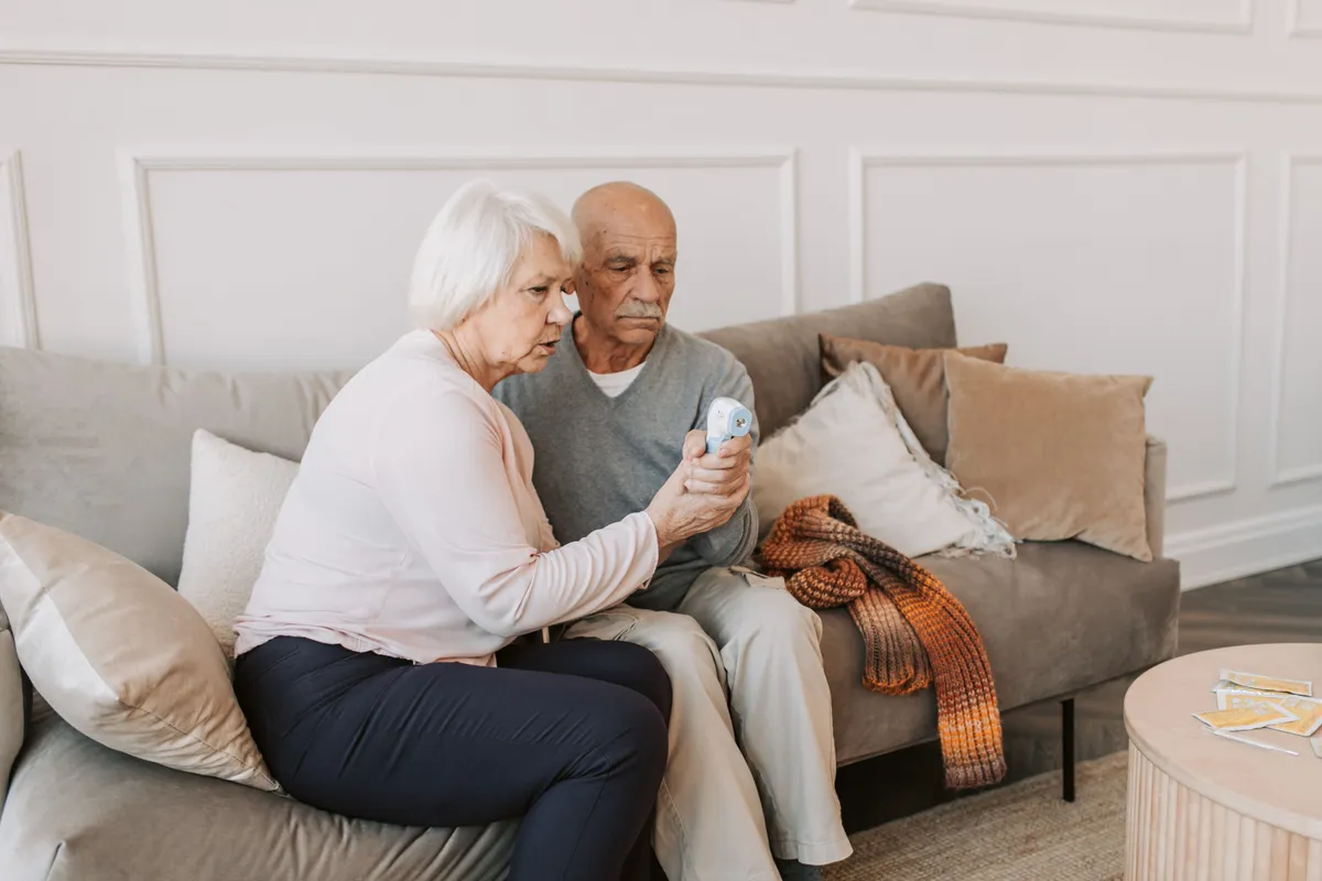 A caregiver taking a health reading for a senior client at home